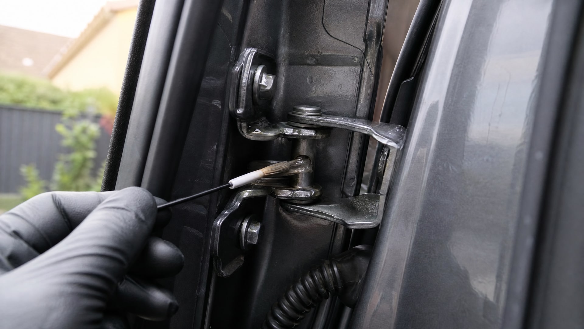 Тонкий слой смазки WD40 на дверной петле автомобиля.