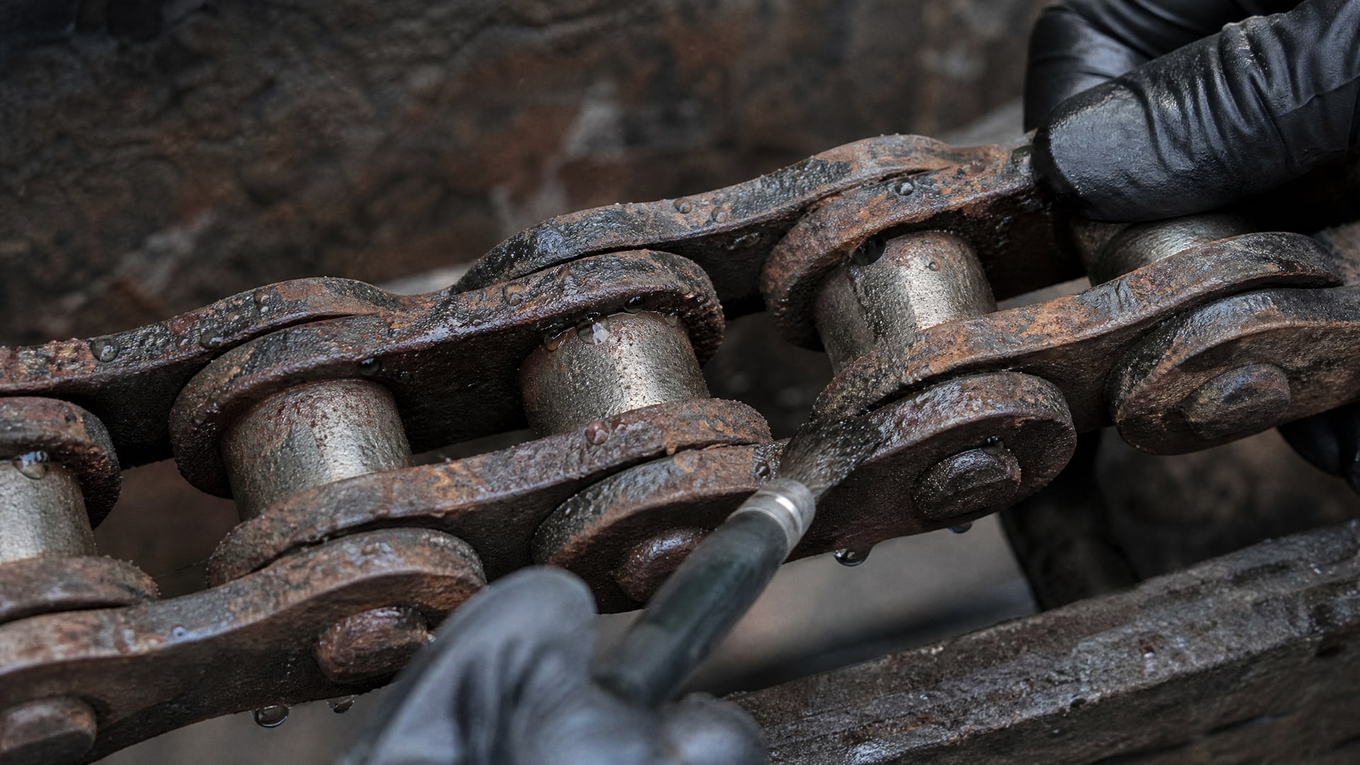 Ржавчина и капли воды на звене цепи с облупившимся сухим покрытием, демонстрируя слабую влагостойкость.