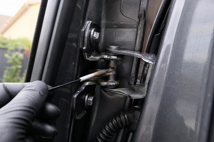 Тонкий слой смазки WD40 на дверной петле автомобиля.